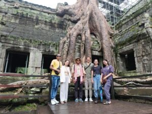 a group of people posing for a photo in front of a tree-Angkor Wat