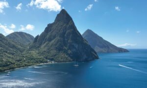 a large mountain with a sailboat in the water with Pitons in the background.Island Bliss